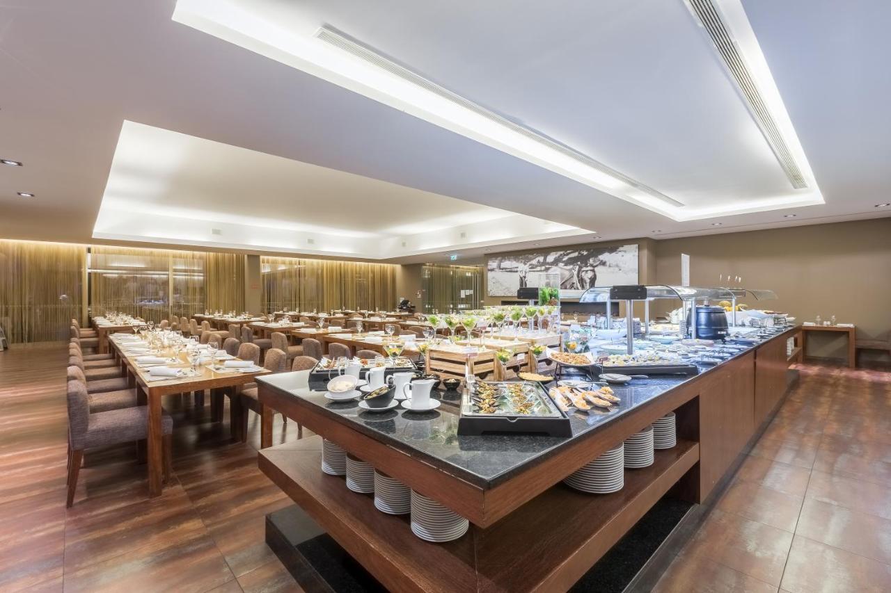 Ap Lago Montargil - Conference & Spa Εξωτερικό φωτογραφία The photo displays a spacious restaurant interior, featuring a well-organized dining area with multiple tables set for patrons. In the center, there is a large buffet station filled with an array of food items. The decor is modern and elegant, with w