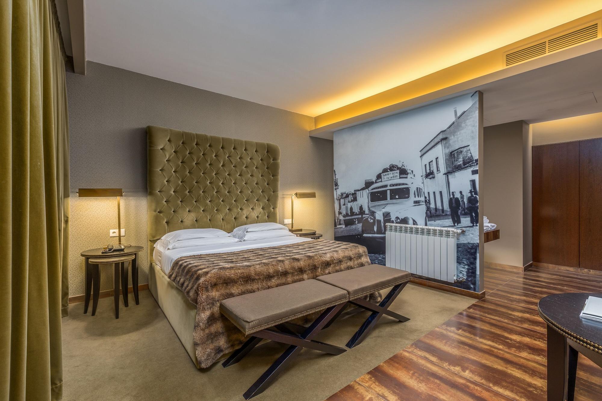 Ap Lago Montargil - Conference & Spa Εξωτερικό φωτογραφία The photo shows a modern hotel room featuring a king-sized bed with a tufted headboard, dressed in white linens and a decorative throw blanket. On either side of the bed, there are bedside tables with lamps. The room is well-lit, with an ambient ceil