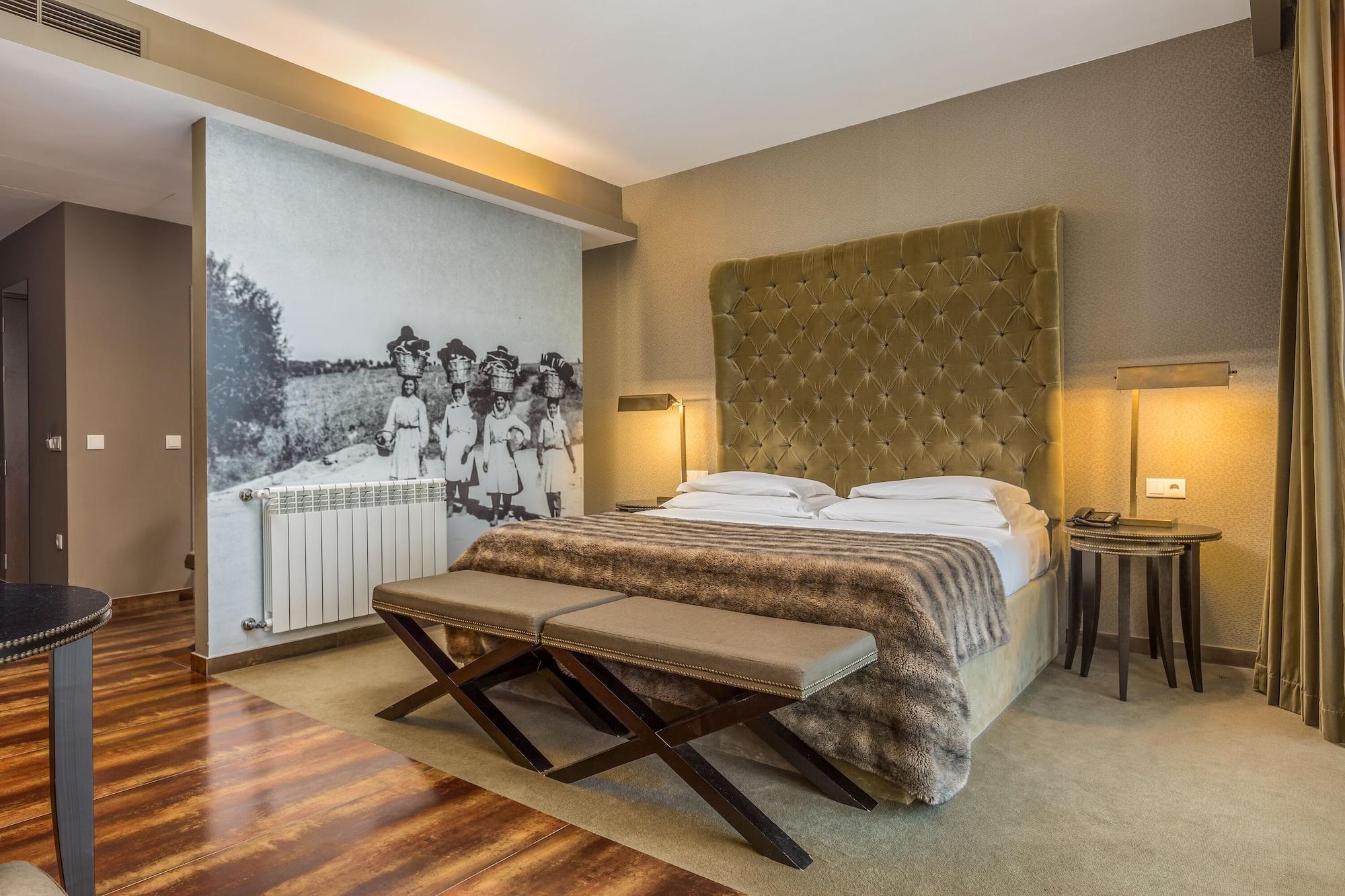 Ap Lago Montargil - Conference & Spa Εξωτερικό φωτογραφία The photo shows a modern hotel room with a large, plush bed that has a tufted, green headboard. The bedding is white with a textured blanket at the foot of the bed. A decorative wall behind the bed features a black and white mural of children in a fi