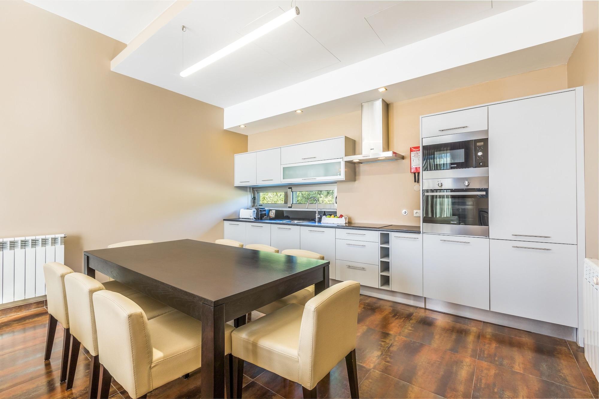 Ap Lago Montargil - Conference & Spa Εξωτερικό φωτογραφία The photo shows a modern kitchen with a dining area. The kitchen features sleek, light-colored cabinets and countertops, including built-in appliances. There's a medium-sized dining table with dark wood and four light-colored chairs around it. The wa